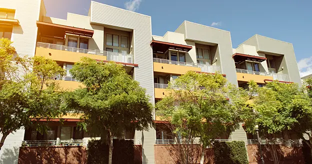 Modern condominium with trees in front.
