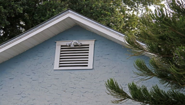 A closeup of the side of a house with blue stucco siding.