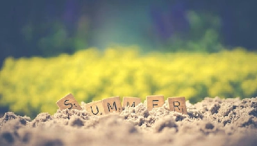 Tiles with letters that spell out summer in the sand.