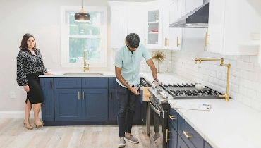 Two people inspecting kitchen drawers in modern kitchen.